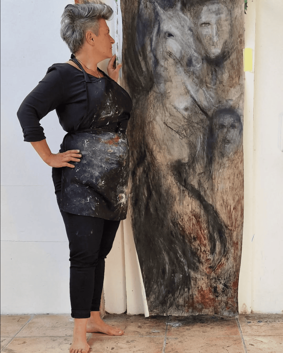 Bild Kathrin Ryan vor Gemälde aus Ausstellung Peace Container I: Heimatlos